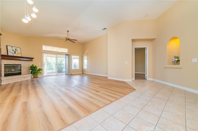 living room featuring a tile fireplace, baseboards, and light tile patterned floors