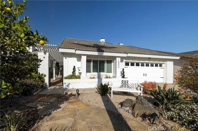 back of property featuring a garage, a tile roof, and brick siding