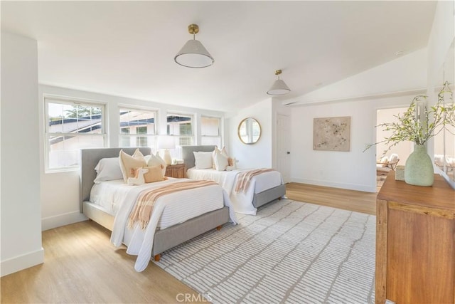 bedroom with lofted ceiling, baseboards, and light wood-type flooring