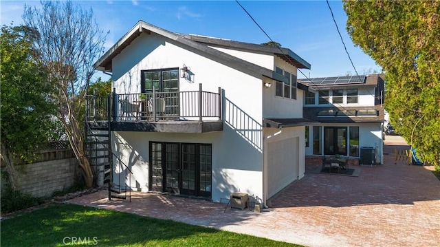 rear view of property featuring a patio, an attached garage, central AC, and stucco siding