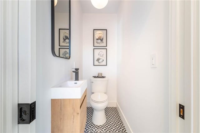 bathroom with toilet, vanity, and baseboards