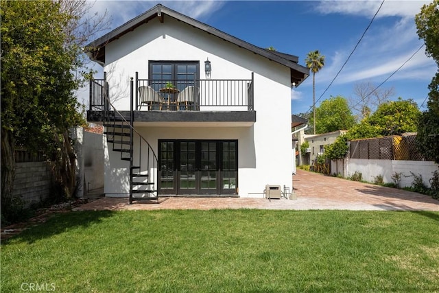 rear view of property with fence, stairway, stucco siding, a yard, and a patio area