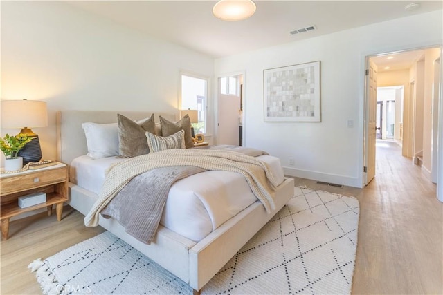 bedroom featuring visible vents, baseboards, and light wood finished floors