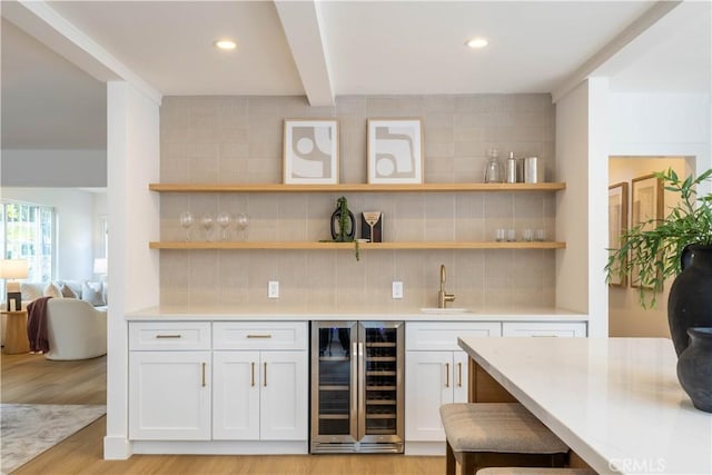 bar with a sink, tasteful backsplash, wine cooler, light wood-style floors, and indoor wet bar