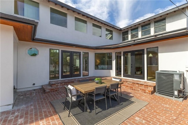 exterior space with outdoor dining space, central AC, stucco siding, french doors, and a patio area