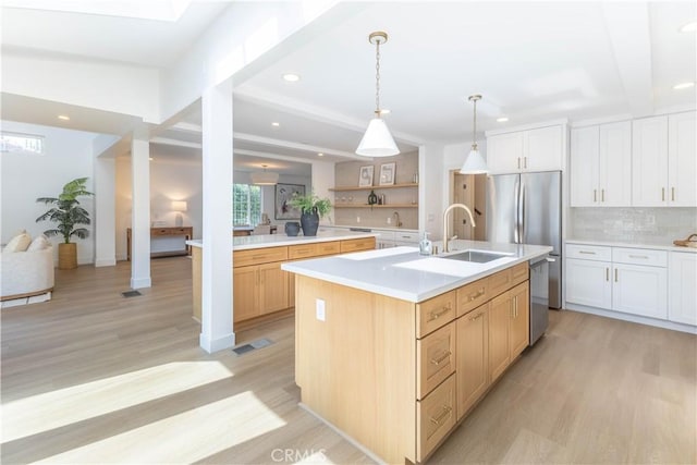 kitchen featuring light wood finished floors, appliances with stainless steel finishes, light countertops, and a sink