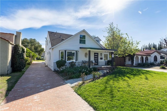 bungalow featuring a front lawn, fence, and covered porch