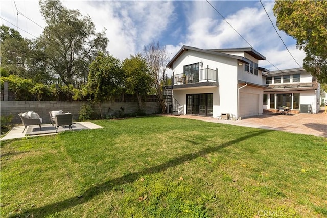 back of house featuring stucco siding, fence, stairway, a yard, and a garage