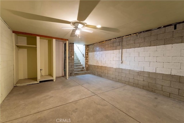 finished below grade area with stairs, concrete block wall, and ceiling fan