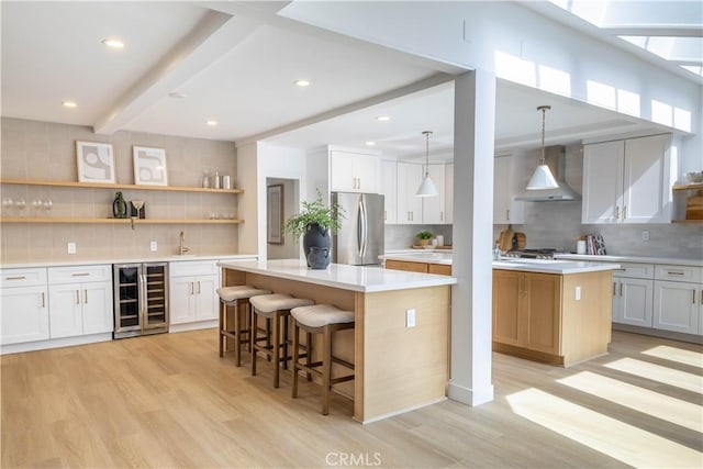 kitchen with a kitchen island, wine cooler, beam ceiling, freestanding refrigerator, and wall chimney exhaust hood