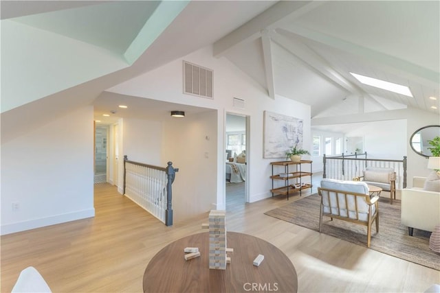 living area with beam ceiling, visible vents, a skylight, and light wood-style floors