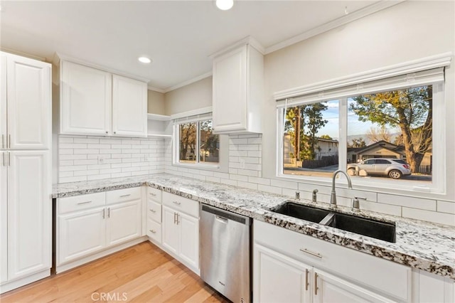 kitchen with a sink, white cabinets, stainless steel dishwasher, backsplash, and light stone countertops