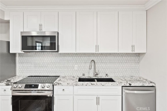 kitchen with a sink, white cabinetry, appliances with stainless steel finishes, backsplash, and light stone countertops