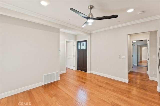 spare room featuring light wood finished floors, visible vents, ornamental molding, ceiling fan, and baseboards