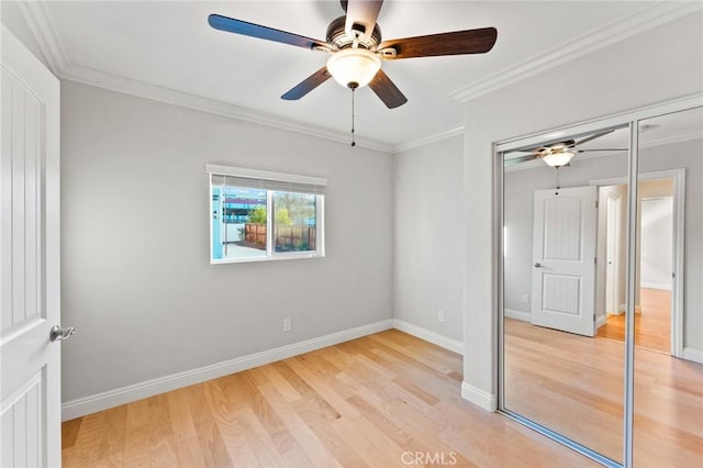 unfurnished bedroom featuring a ceiling fan, baseboards, a closet, light wood finished floors, and crown molding