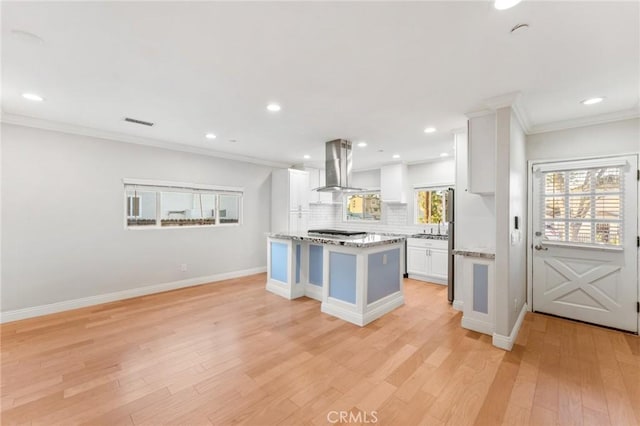 kitchen with island exhaust hood, visible vents, backsplash, light wood-style floors, and white cabinetry