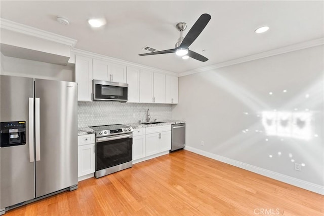 kitchen featuring stainless steel appliances, visible vents, white cabinetry, a sink, and light stone countertops