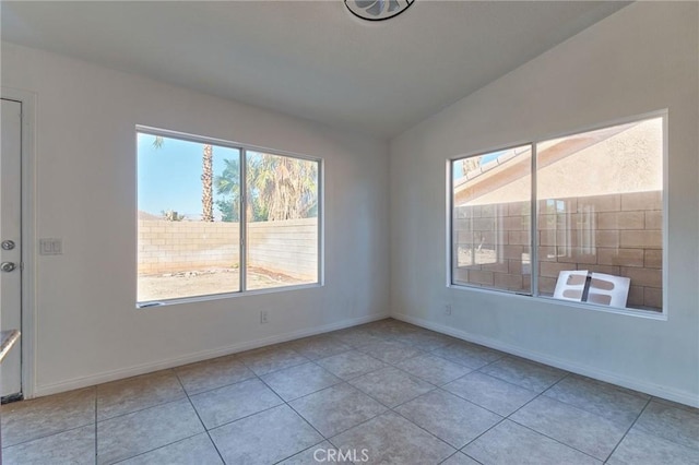 spare room with baseboards, vaulted ceiling, and light tile patterned flooring