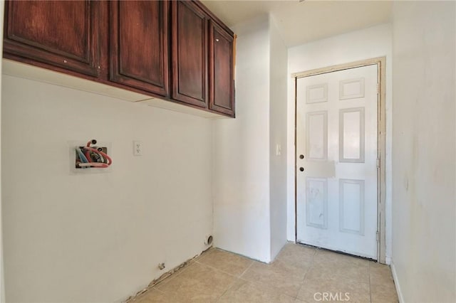 clothes washing area featuring cabinet space and light tile patterned flooring