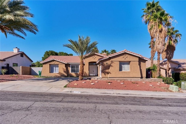 mediterranean / spanish home featuring driveway, fence, a tile roof, and stucco siding