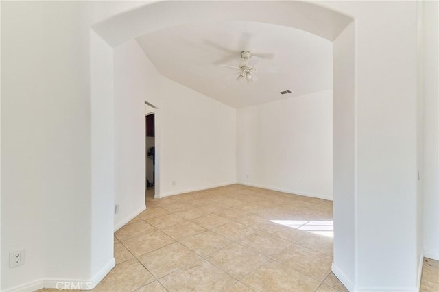 empty room with arched walkways, ceiling fan, baseboards, and light tile patterned floors