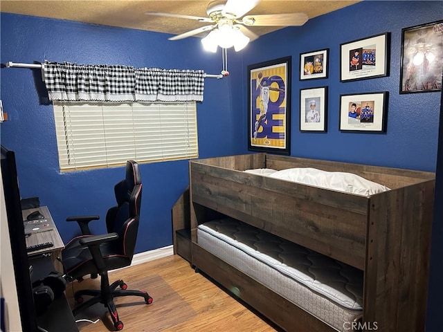 bedroom featuring a ceiling fan, wood finished floors, and a textured wall