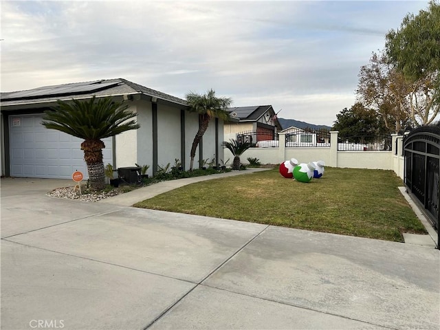 view of front of property featuring a garage, solar panels, concrete driveway, a fenced front yard, and stucco siding