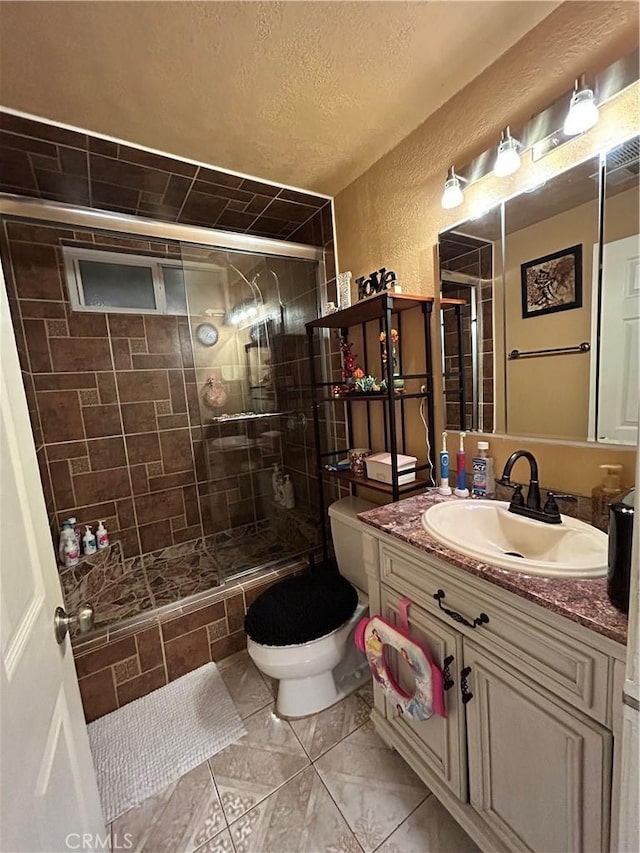 full bath featuring toilet, a textured wall, a shower stall, and vanity