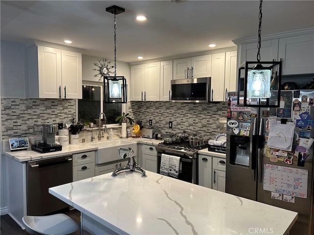 kitchen with appliances with stainless steel finishes, decorative light fixtures, and white cabinets