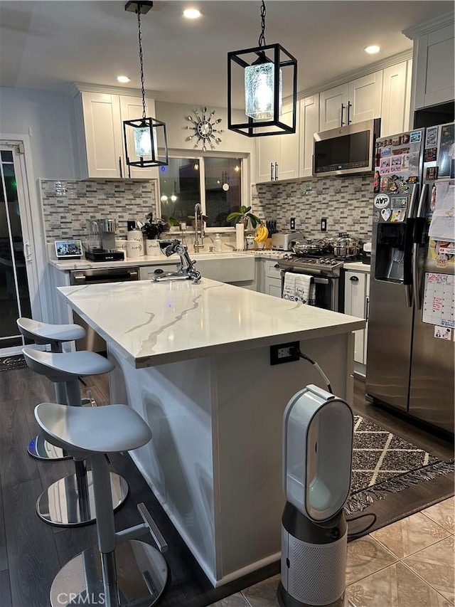 kitchen with hanging light fixtures, appliances with stainless steel finishes, a kitchen bar, and white cabinetry