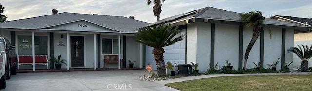 view of front of house with a front yard, concrete driveway, an attached garage, and stucco siding