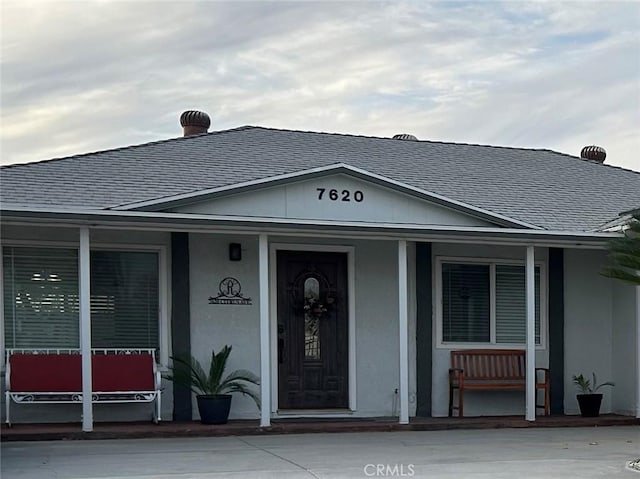 view of front of home featuring a porch, roof with shingles, and stucco siding