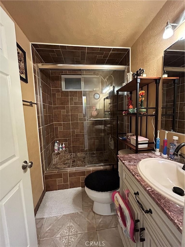 bathroom featuring a textured wall, toilet, tile patterned floors, vanity, and a shower stall