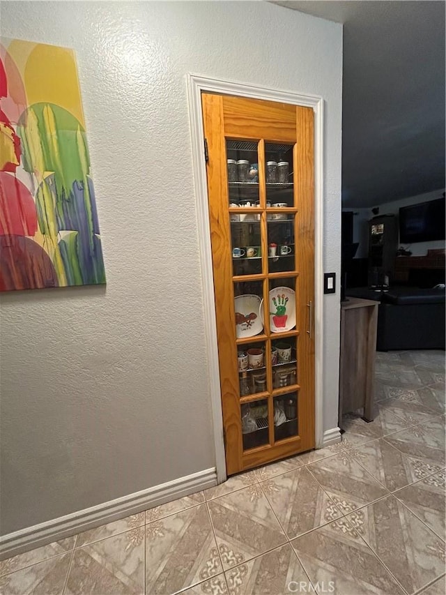 interior space featuring a textured wall and baseboards