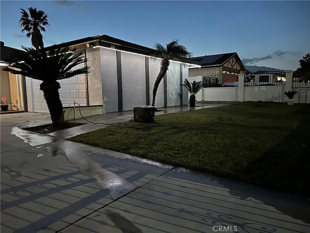 view of property exterior featuring a yard, fence, and stucco siding