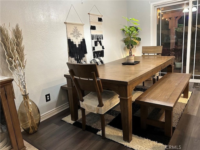 dining area featuring dark wood-style floors, baseboards, and a textured wall