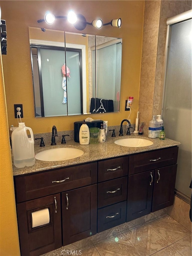 full bathroom with double vanity, marble finish floor, a shower stall, and a sink