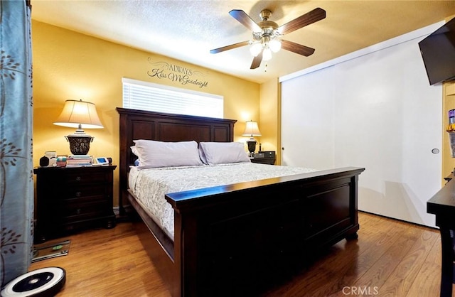 bedroom featuring a ceiling fan, wood finished floors, and a closet