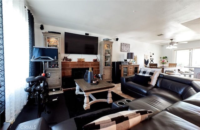 living area with a ceiling fan, visible vents, and a tiled fireplace