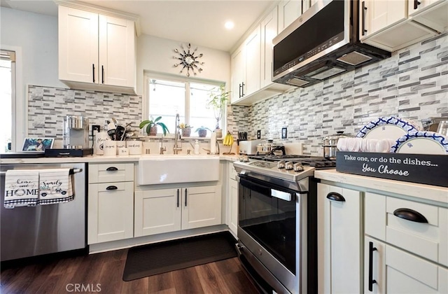 kitchen with white cabinets, stainless steel appliances, a sink, tasteful backsplash, and light countertops