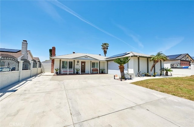 view of front of property featuring solar panels, driveway, fence, and a garage