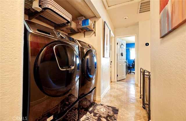 clothes washing area with a textured wall, laundry area, washer and clothes dryer, and visible vents