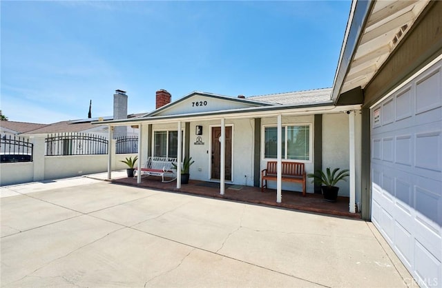 view of front of property featuring stucco siding, fence, a chimney, and covered porch