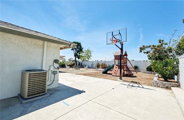 view of basketball court featuring a fenced backyard and a playground