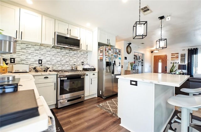 kitchen featuring tasteful backsplash, stainless steel appliances, dark wood-style flooring, visible vents, and a kitchen island