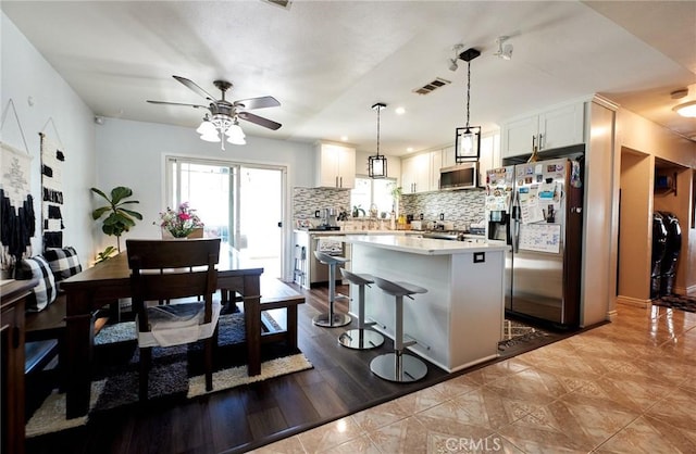 kitchen with white cabinets, visible vents, a ceiling fan, tasteful backsplash, and appliances with stainless steel finishes