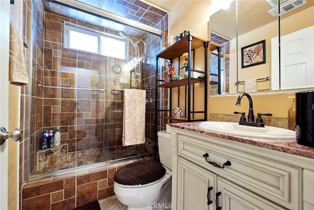 bathroom featuring tiled shower, visible vents, vanity, and toilet