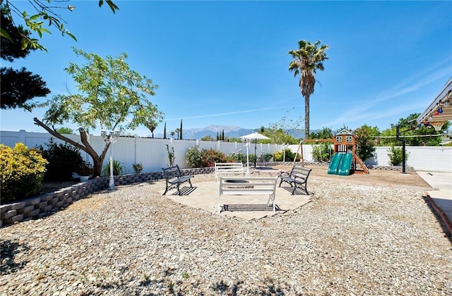 view of yard with a fenced backyard, a mountain view, a patio area, and a playground