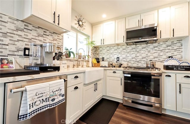 kitchen featuring white cabinets, stainless steel appliances, a sink, tasteful backsplash, and light countertops