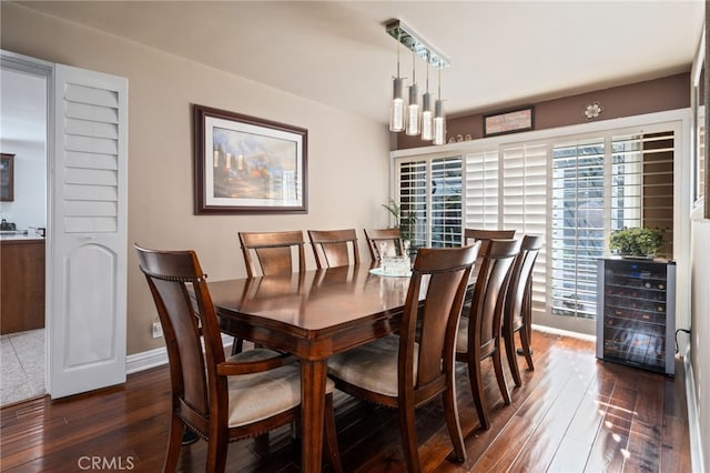 dining room featuring dark wood-type flooring, wine cooler, and baseboards